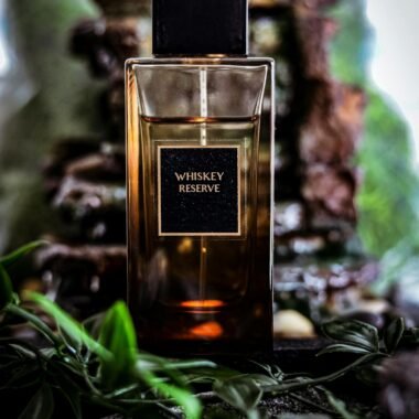 Elegant Whiskey Reserve perfume bottle surrounded by leaves, exuding luxury and nature.