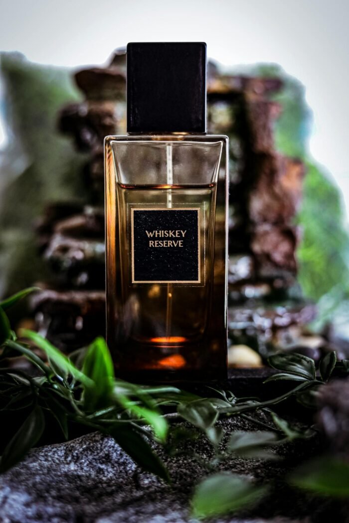 Elegant Whiskey Reserve perfume bottle surrounded by leaves, exuding luxury and nature.
